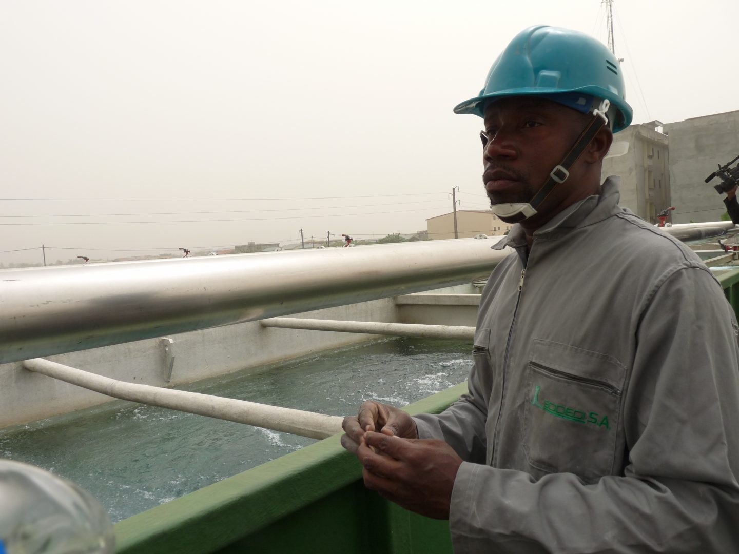 Man in a blue hard hat looks out over machinery