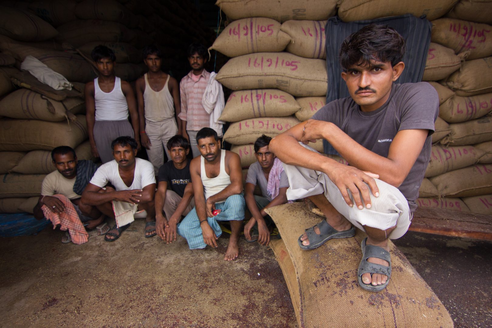 Men crouch on top of bags of corn