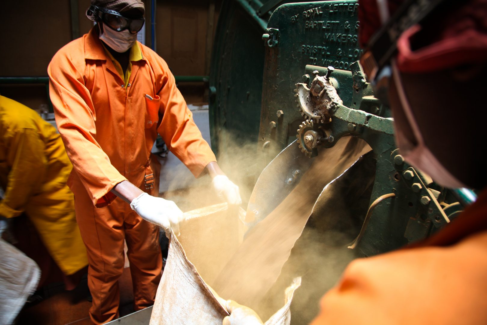 Worker fills sack with dust from a machine