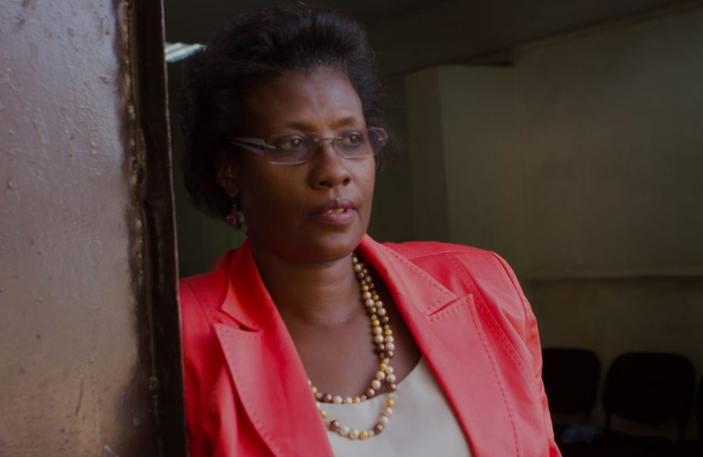 Woman in pink blazer leans against a wall