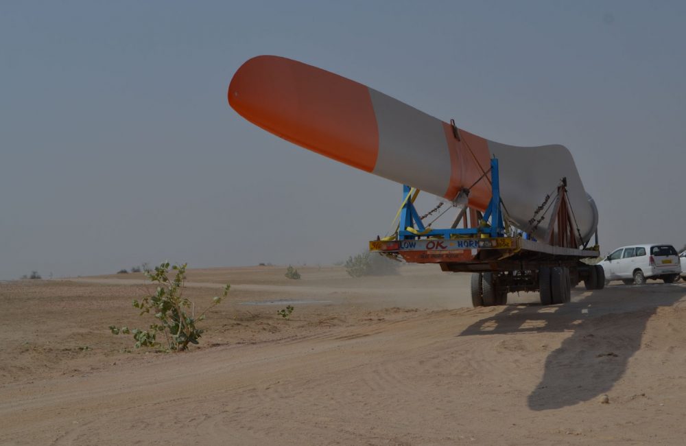 A wind turbine blade gets transported on the back of a trailer