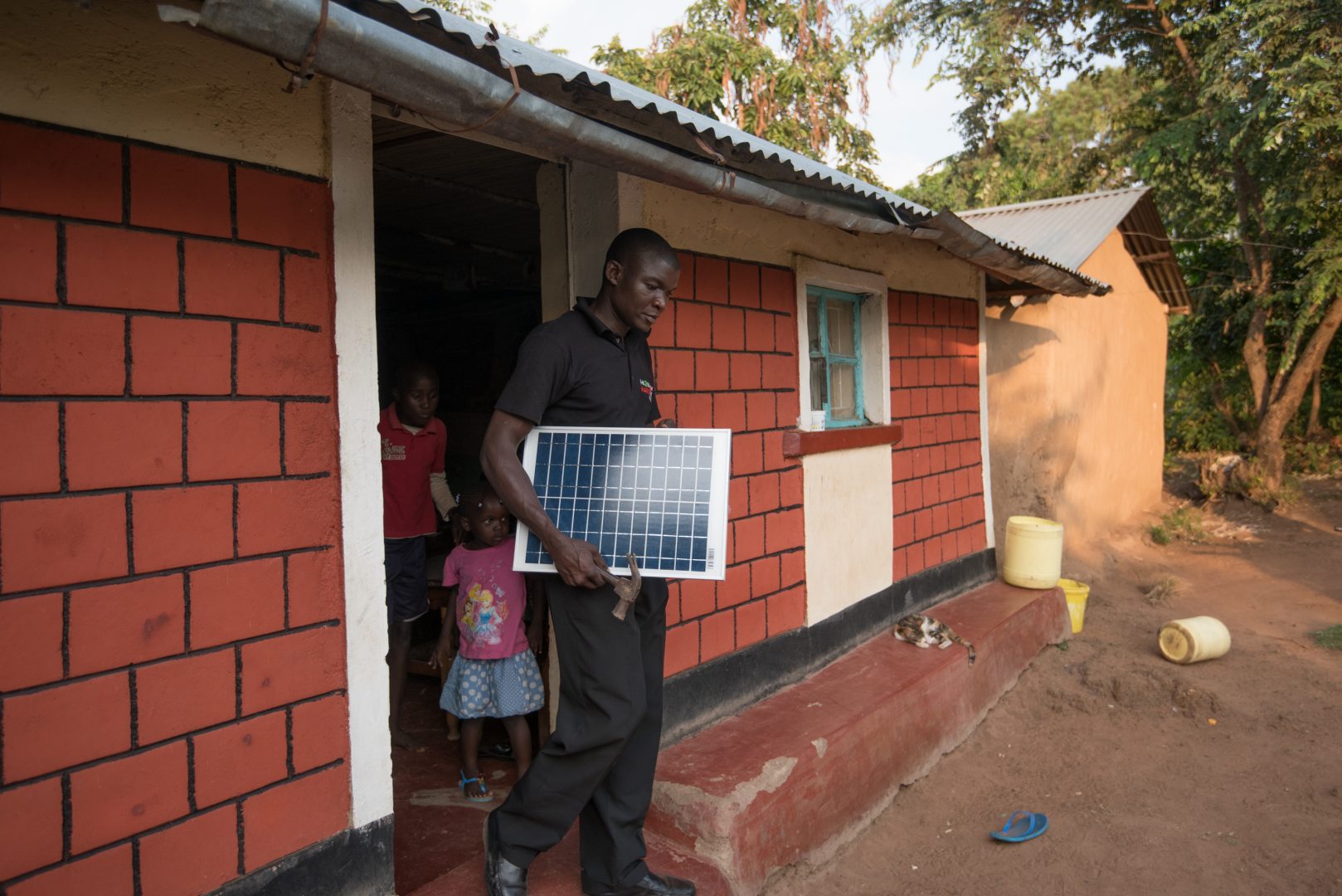 Man carries a solar panel out of a red brick building