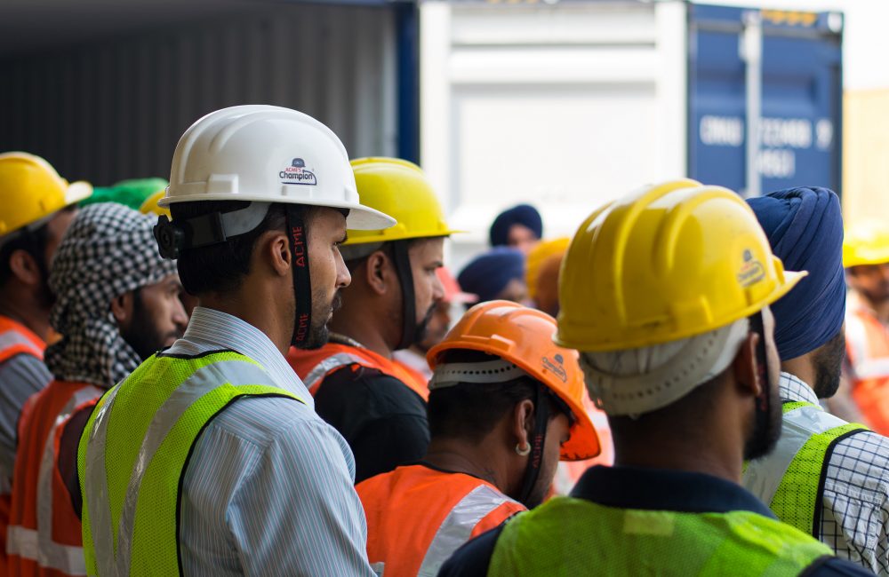 Men gathered around all wearing hard hats