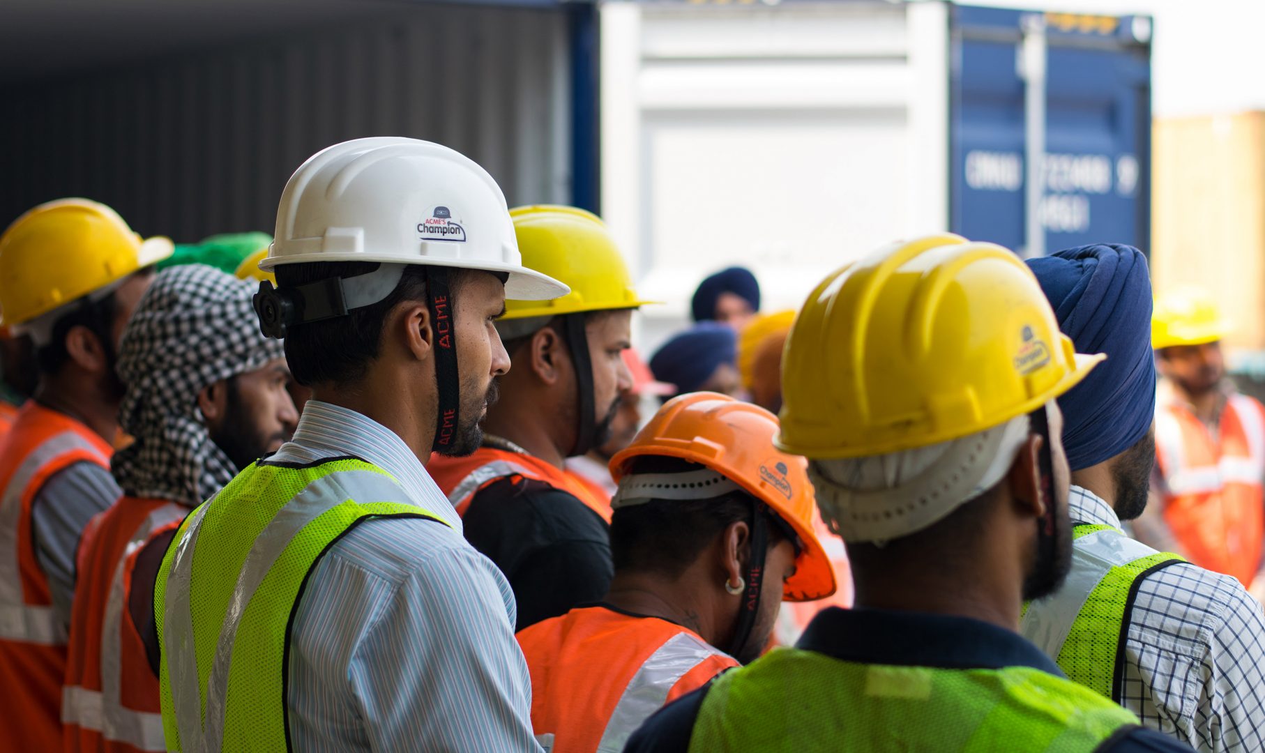 Men gathered around all wearing hard hats